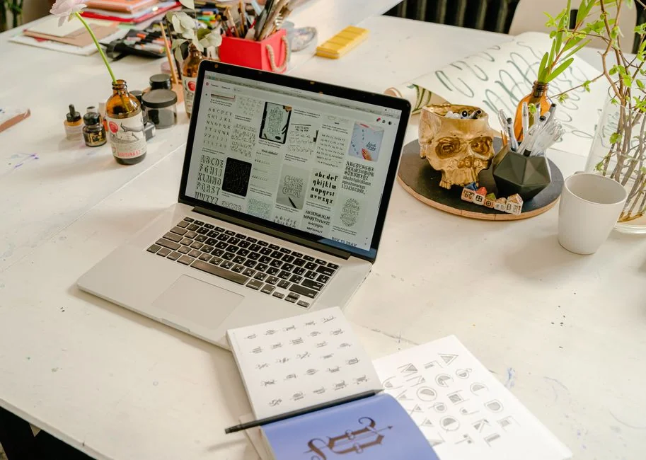 Un écran d'ordinateur portable affiche une application de codage avec un design de calculatrice dans un environnement de bureau technologique.
